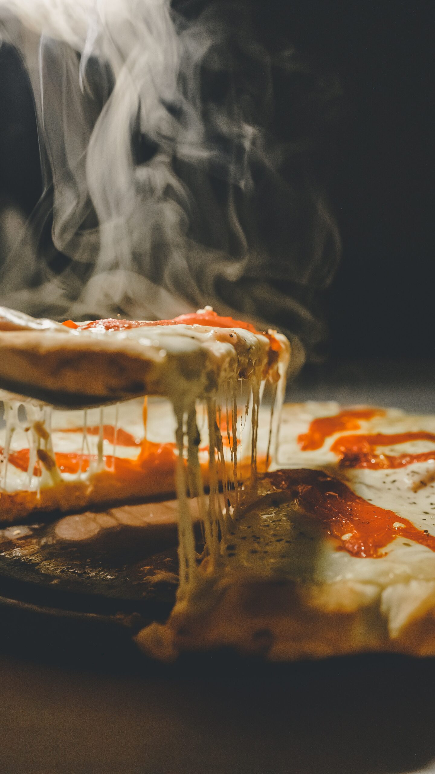 a person taking a slide of a cheesy pizza like a Chicago Style