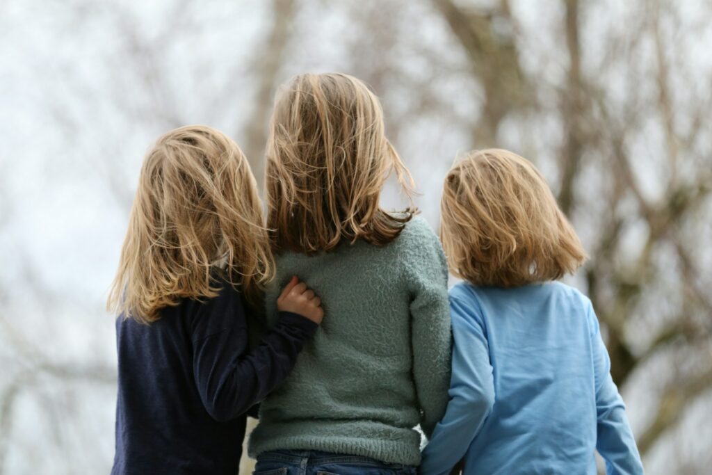 a photo of the back of three person near each other that are siblings