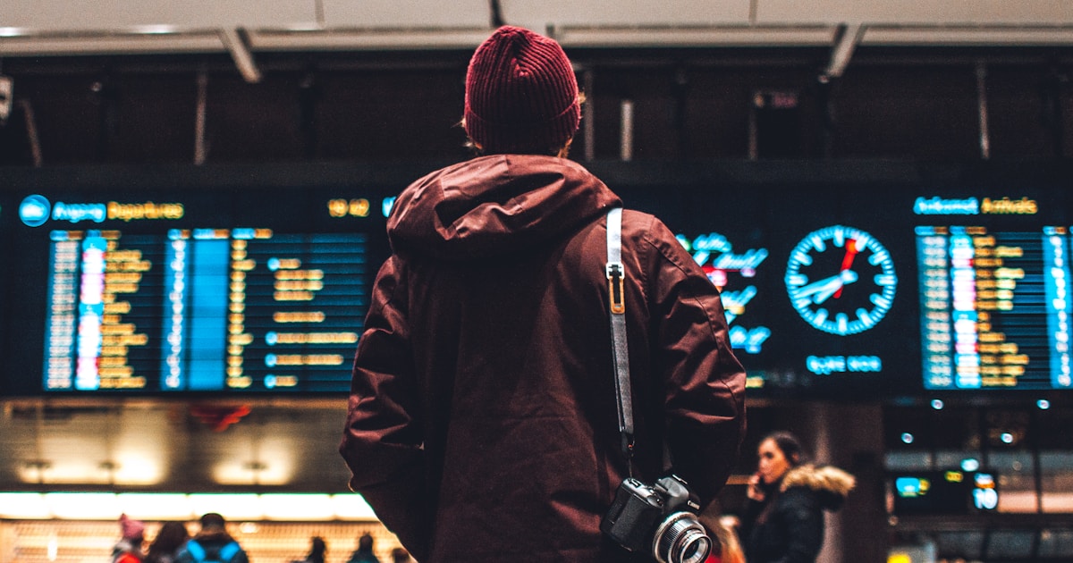 Woman traveler at airport terminal with luggage looking at flights